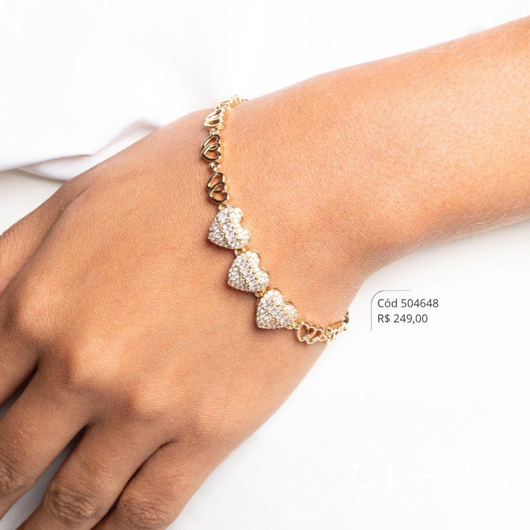 PULSEIRA ELOS CORAÇÕES ENTRELAÇADOS C/ 3 CORAÇÕES MICROZIRCÔNIAS C/ MEIO ZIRCÔNIA BAGUETE FIXOS C/ FECHO GAVETA ITALIANO - 10MM - 17CM - Dourado